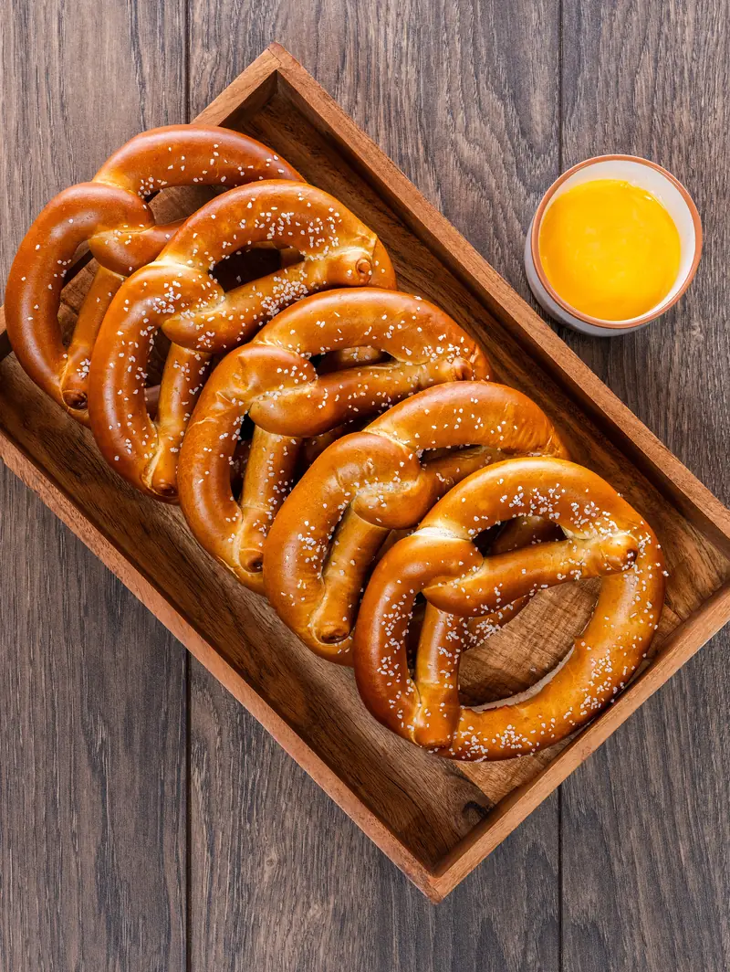 Five oz Bavarian twists in a wooden tray with a cheese dip